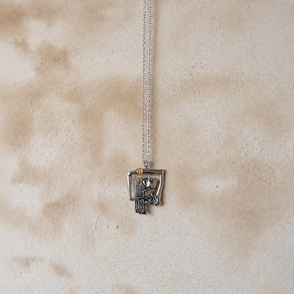 Silver-tone abstract woman pendant necklace with a small gold-tone accent on a neutral background Bali inspired stone 