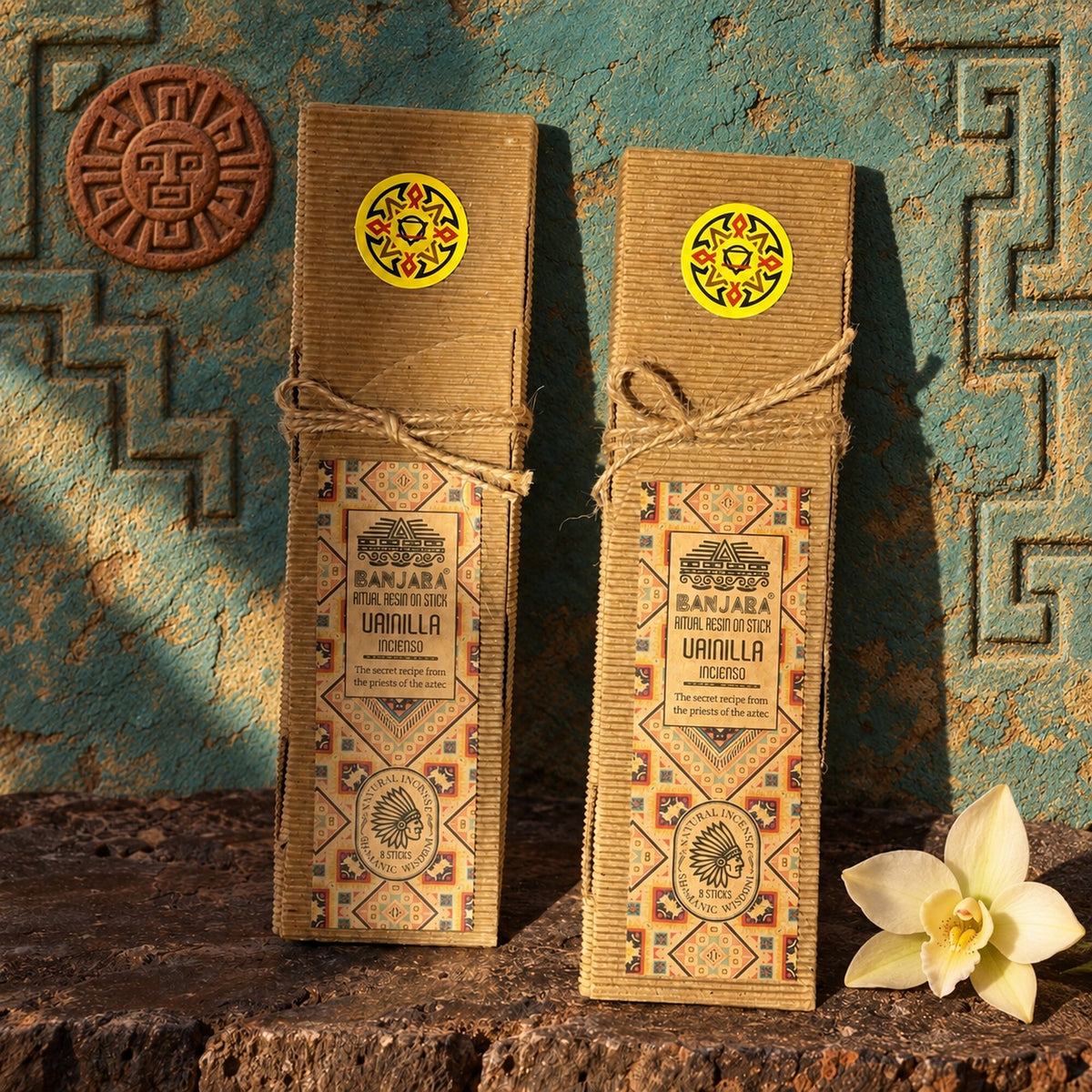 Banjara Vanilla Ritual Resin on Stick incense boxes displayed in an Aztec-inspired styled setting with vanilla flower.