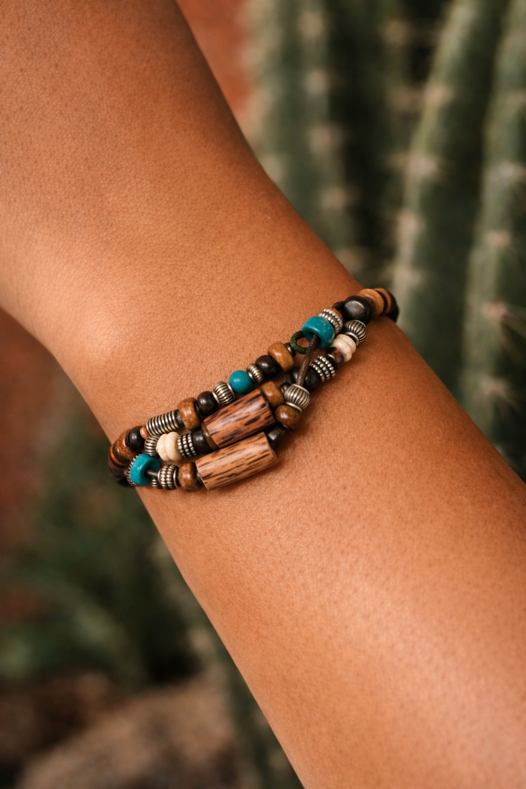 Model wearing a boho adjustable cord bracelet set with brown, black and turquoise-look beads and silver-tone spacers.