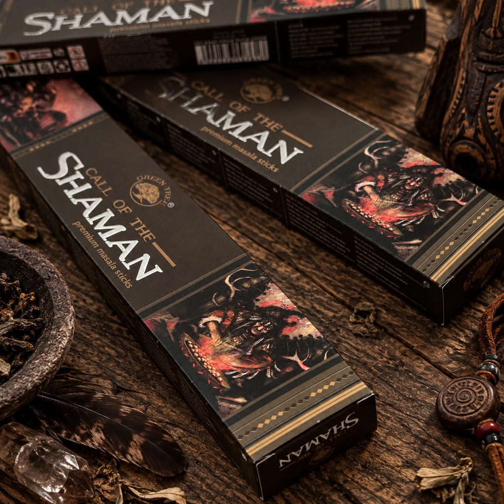 Close-up of Green Tree Call of the Shaman premium masala incense boxes in a dark earth-toned setting with feathers, herbs and rustic accessories.