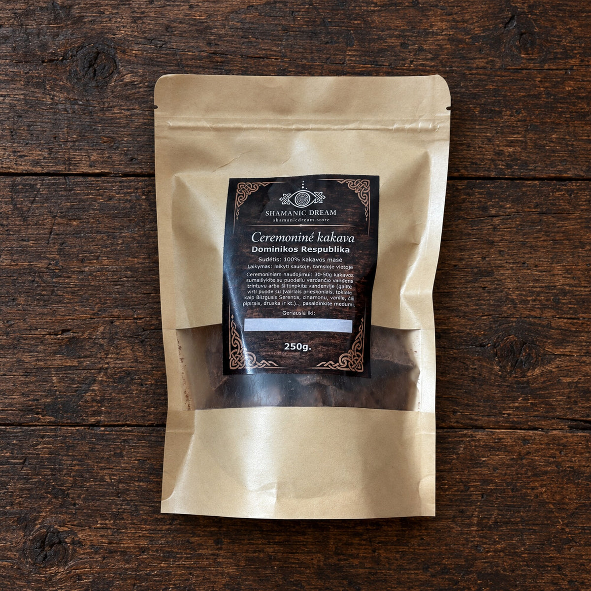 250 g pouch of Shamanic Dream ceremonial cacao from the Dominican Republic, shown on a dark aged wood surface.