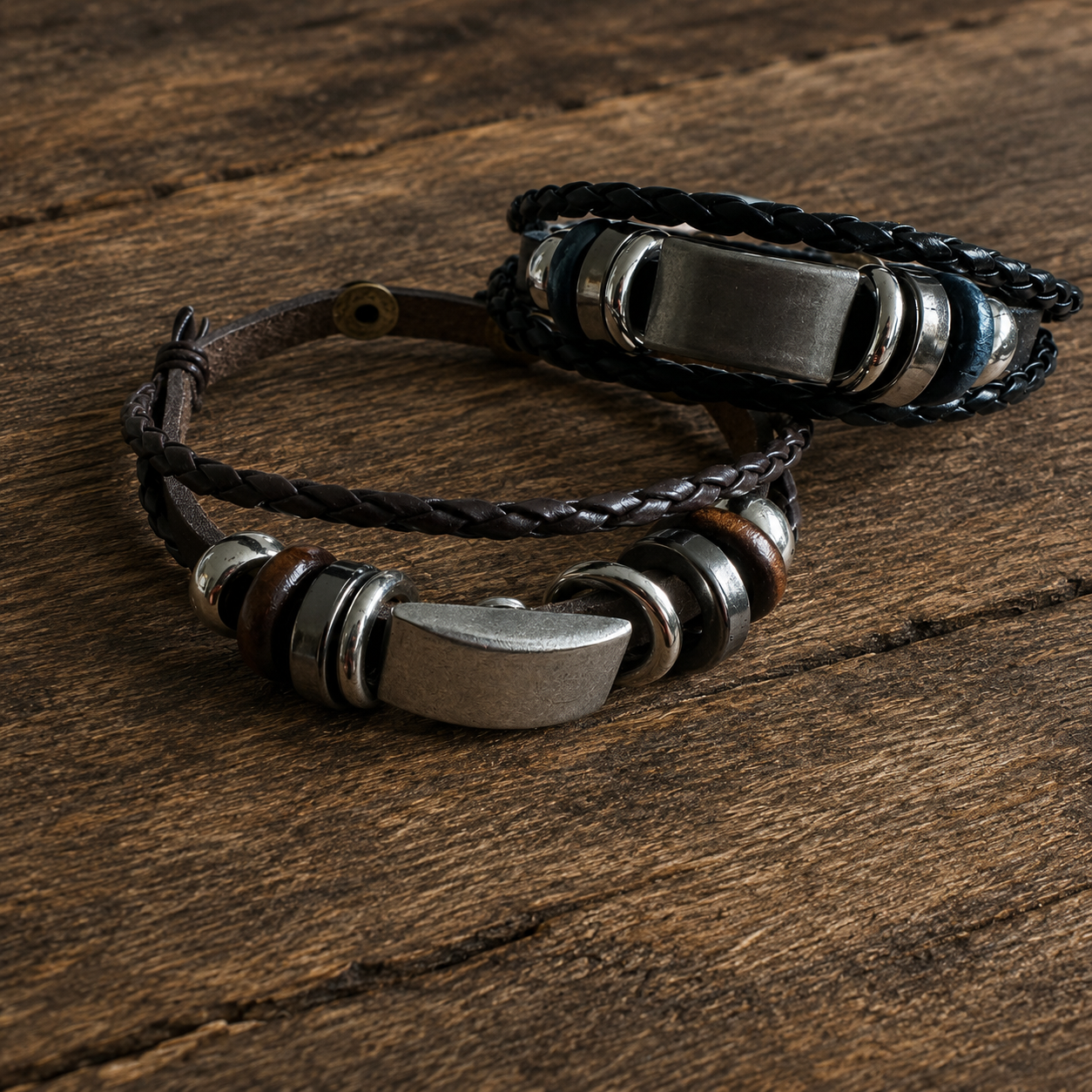Handcrafted adjustable leather bracelets in dark brown and navy black with metallic accents on a wooden surface.