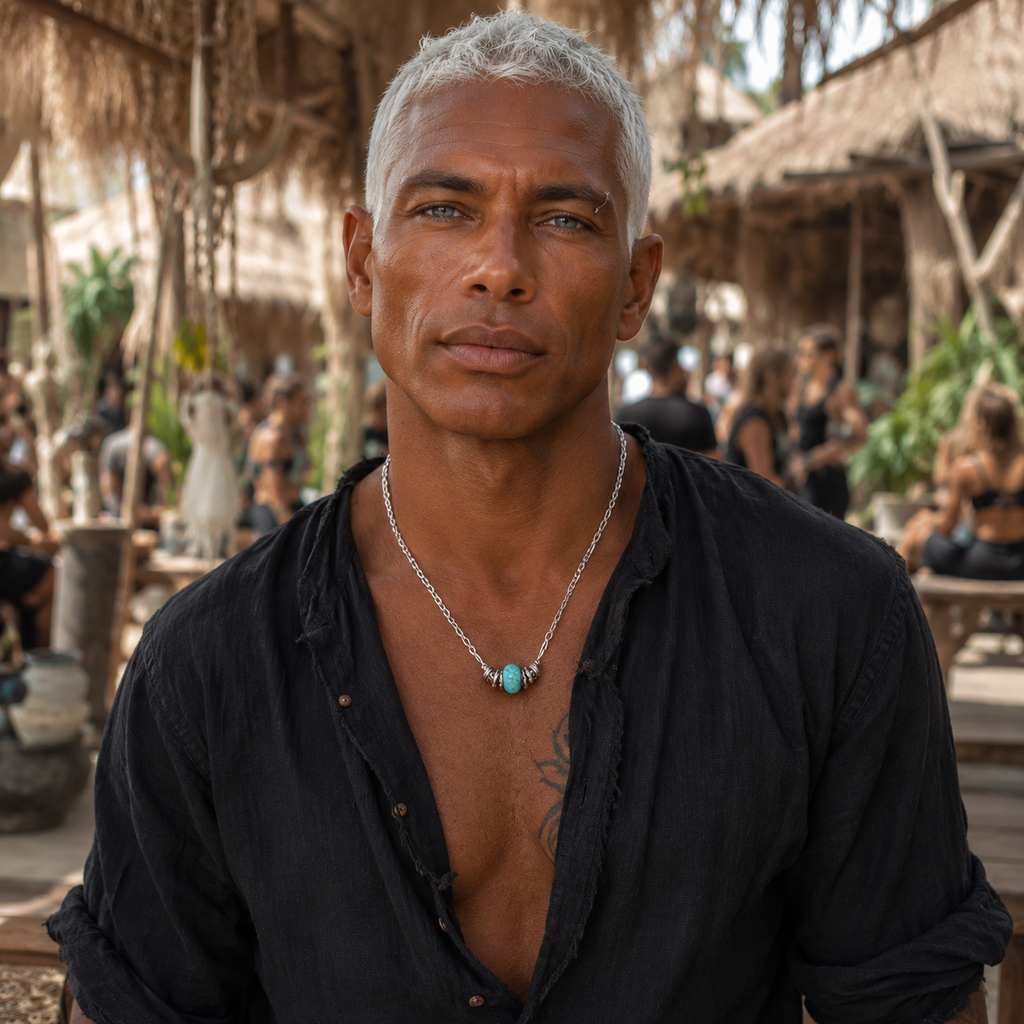Man wearing a handmade blue stone pendant necklace in a tropical outdoor setting