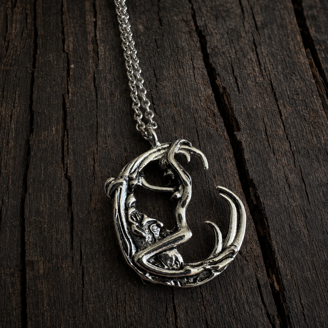 Silver-tone sculptural moon pendant necklace with antiqued detailing on dark rustic wood. Lunar inspired. Unisex design. 