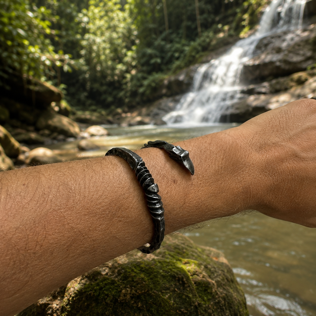 Nordic forged open cuff bracelet worn outdoors near a tropical waterfall.