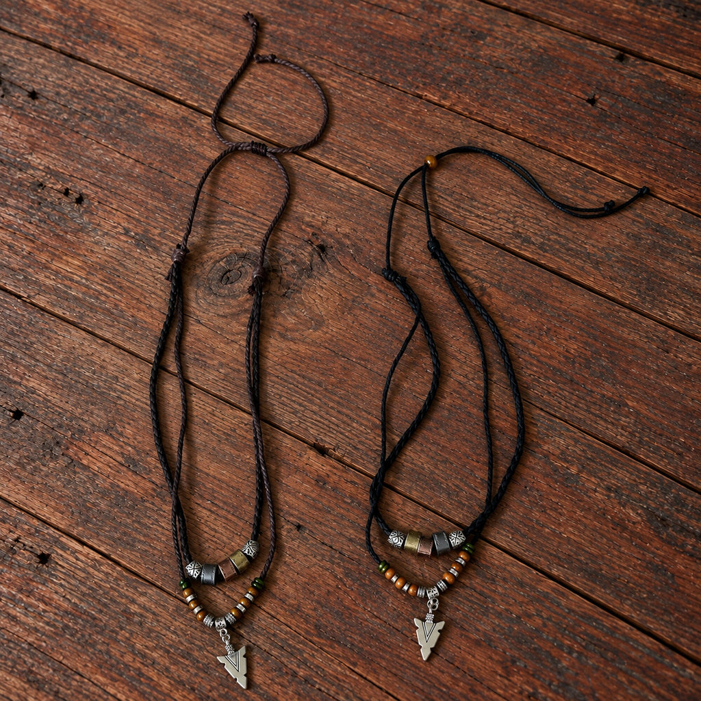 Brown and black Norse Traveller Arrow Amulet necklaces with layered cords, beads and silver-tone arrow pendants.
