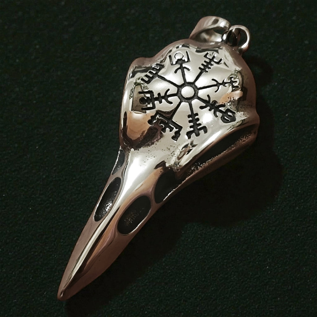 Close-up of a silver-tone raven skull pendant engraved with a Vegvisir-style symbol