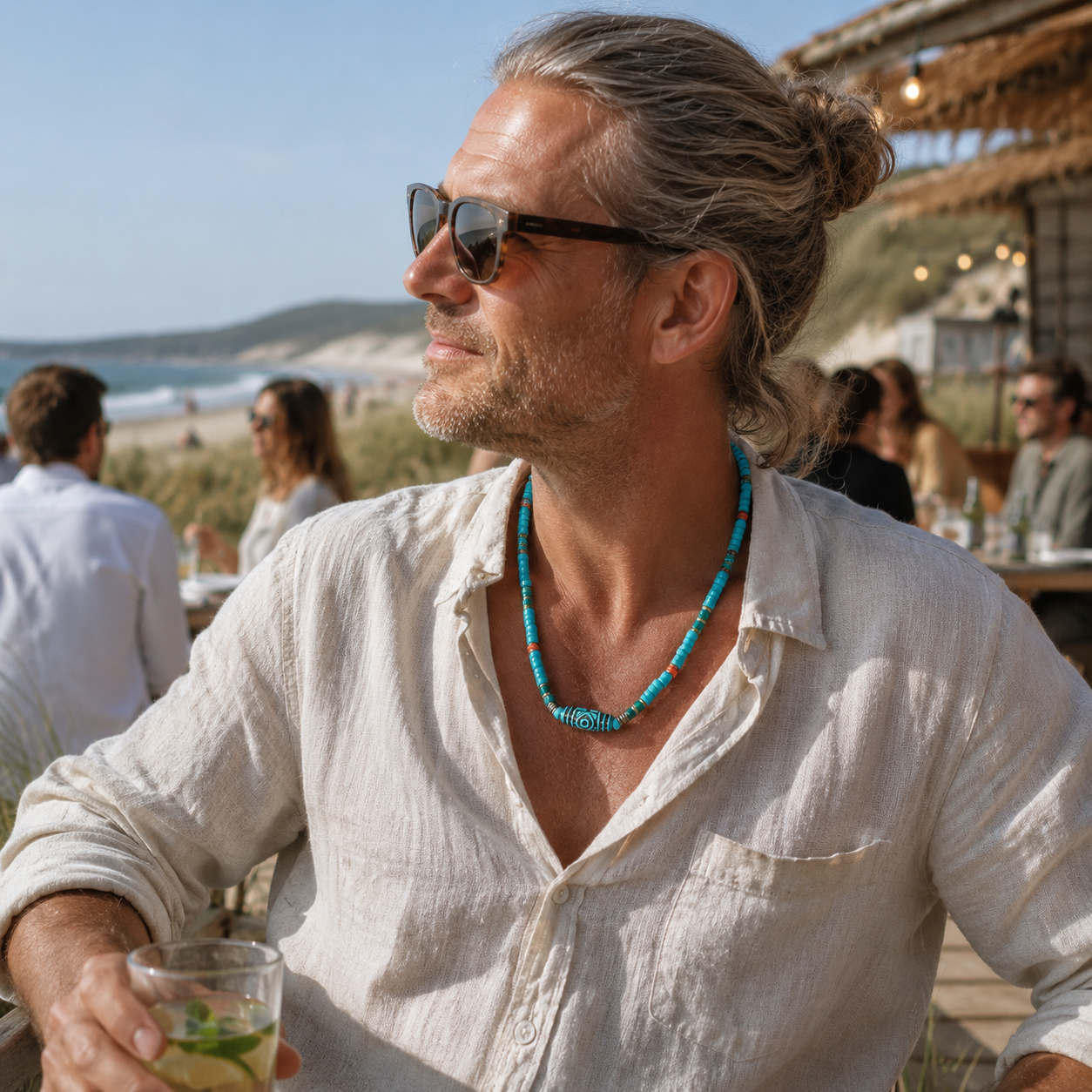 Man wearing an adjustable tribal coastal beaded necklace with a linen shirt at a relaxed beachside setting.